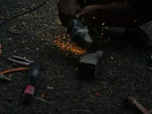 Angle grinder cutting a steel section with sparks