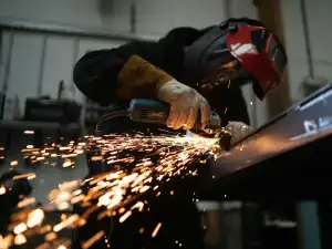 Worker grinding steel in protective gear
