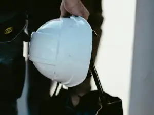 White safety helmet held by its brim