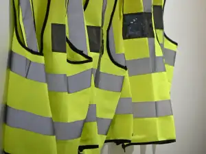 High-visibility vests and helmets hanging on a wall