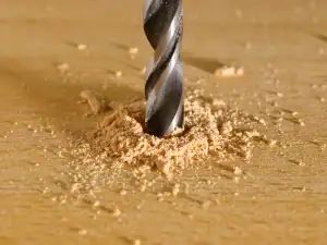 Drill bit boring into a timber board