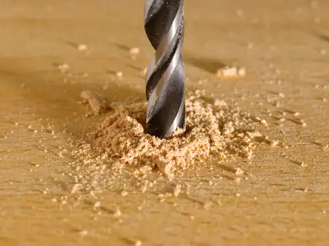 Drill bit boring into a timber board